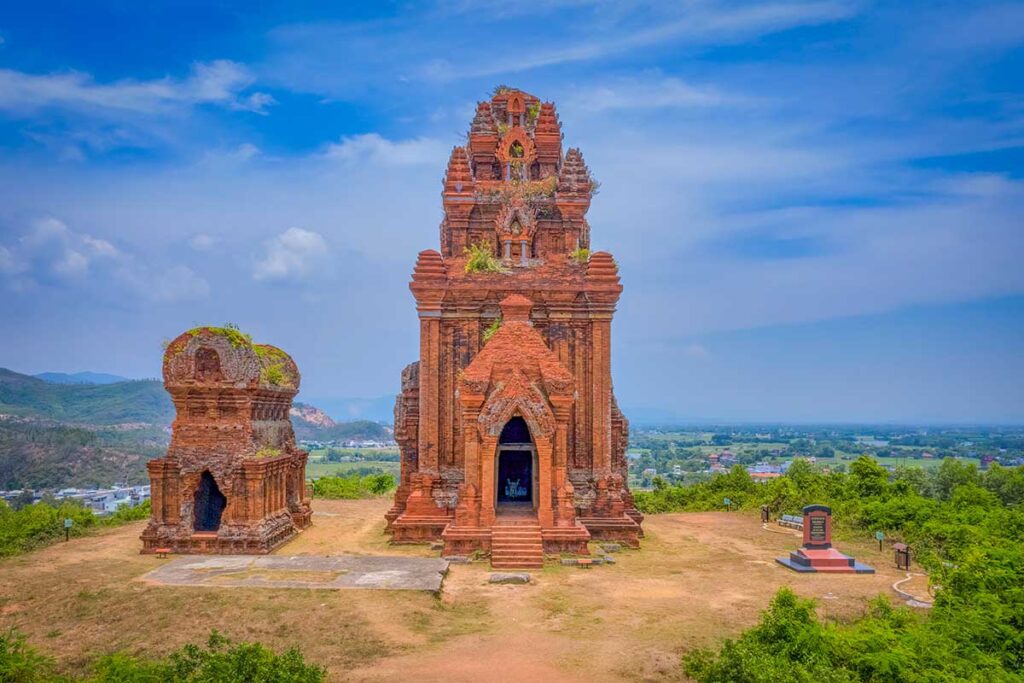 Kalan main tower at Banh It Cham Towers, doorway framing the Shiva statue and hill views.