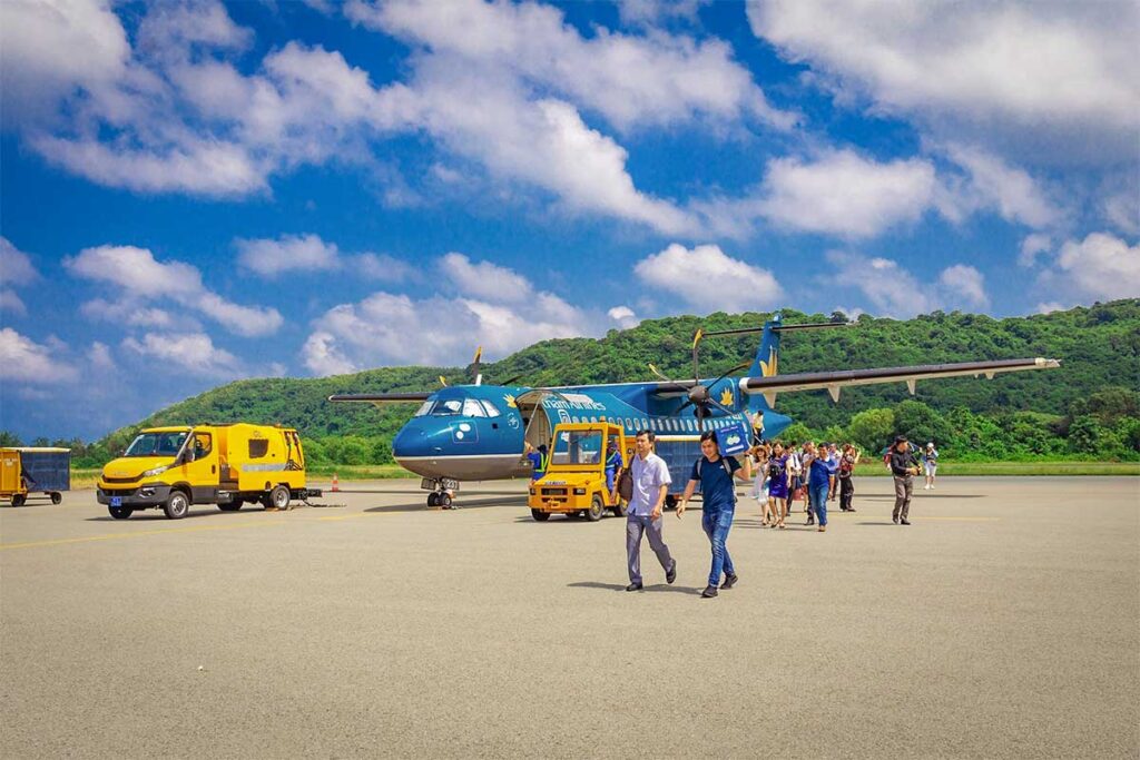 Passengers walking across the runway to board a Vietnam Airlines turboprop aircraft at Con Dao Airport
