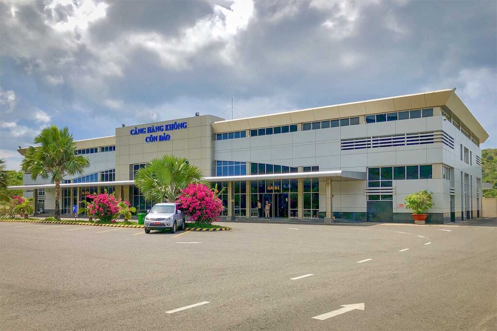 Exterior view of Con Dao Airport terminal building with palm trees and parking area in front