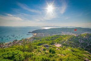 Aerial view of Cu Lao Xanh Island with fishing boats in the bay, the village below, and the Vietnamese flagpole on the ridge.