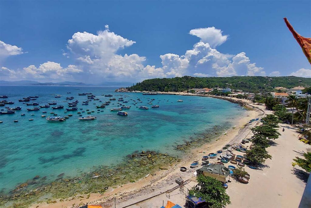 The fishing harbor of Cu Lao Xanh with colorful boats and basket coracles along the shoreline. Best placement: Section about the fishing village and daily life.