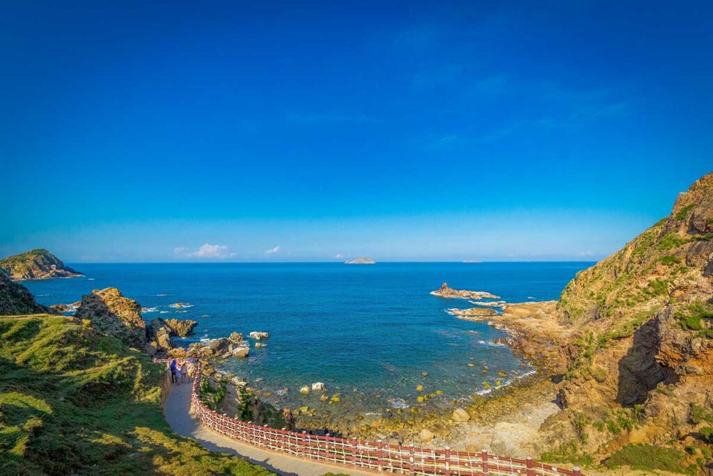 Scenic section of the coastal boardwalk at Eo Gió with blue ocean views and rocky shoreline