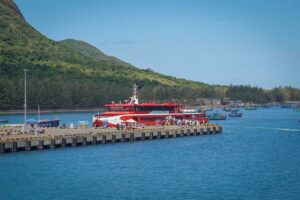 High-speed ferry arriving at Con Dao harbor with clear blue water and green mountains in the background