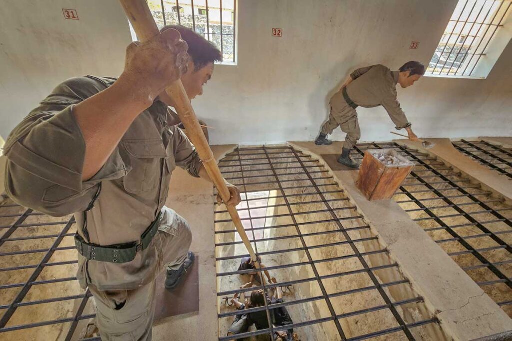 Close-up of a prisoner cell in the French Tiger Cages at Con Dao prison, showing iron bars overhead where guards could watch and control detainees.