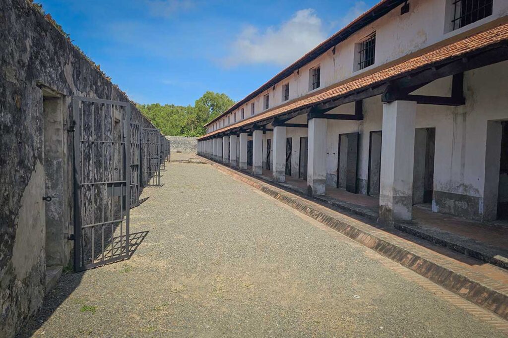 Long row of prison cells and open courtyard inside the French Tiger Cages at Con Dao prison, illustrating the layout of the historical detention complex.