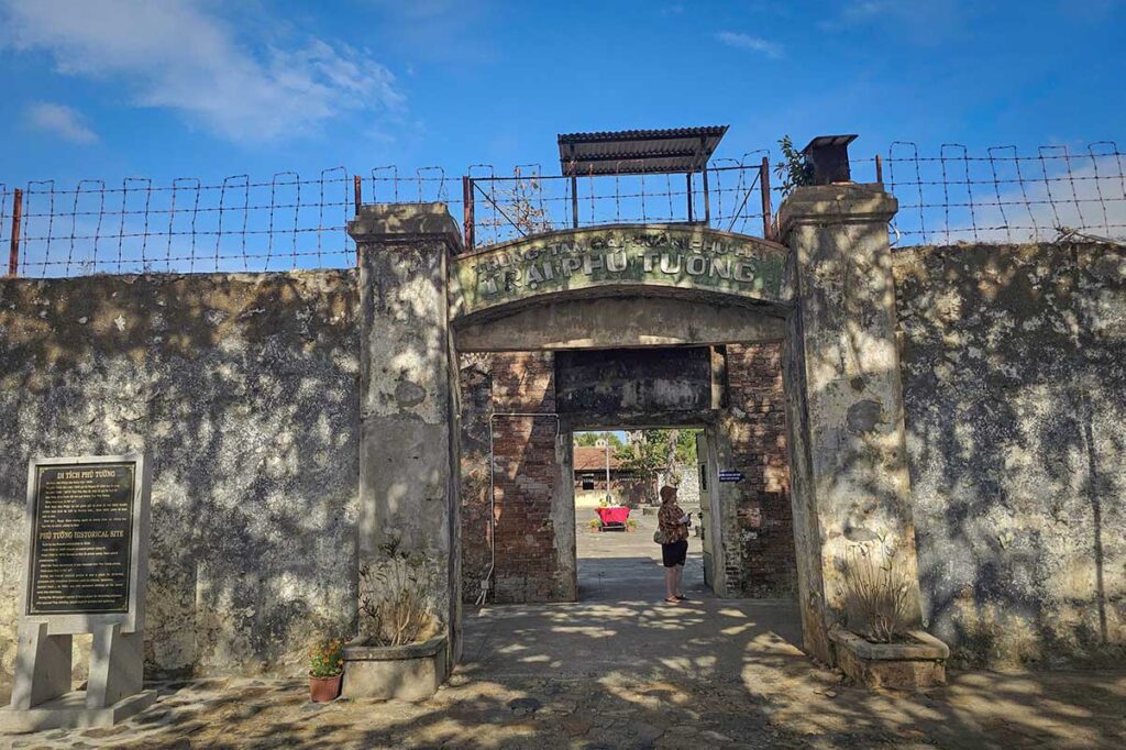 Entrance gate of the French Tiger Cages at Con Dao prison, with high stone walls and barbed wire reflecting the strict security of this colonial-era detention site.
