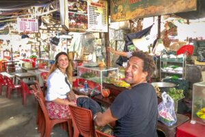 Travelers enjoying authentic local dishes at a traditional market food stall during a Hue street food tour.