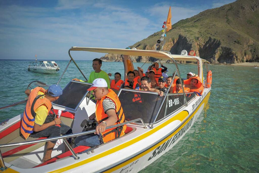 Speedboat tour to Ky Co Beach – Group of tourists in orange life jackets arriving at Ky Co Beach by speedboat.