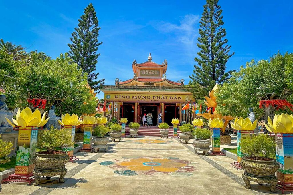 Entrance of Ngọc Hòa Monastery with colorful lotus decorations and Buddhist flags near Eo Gió