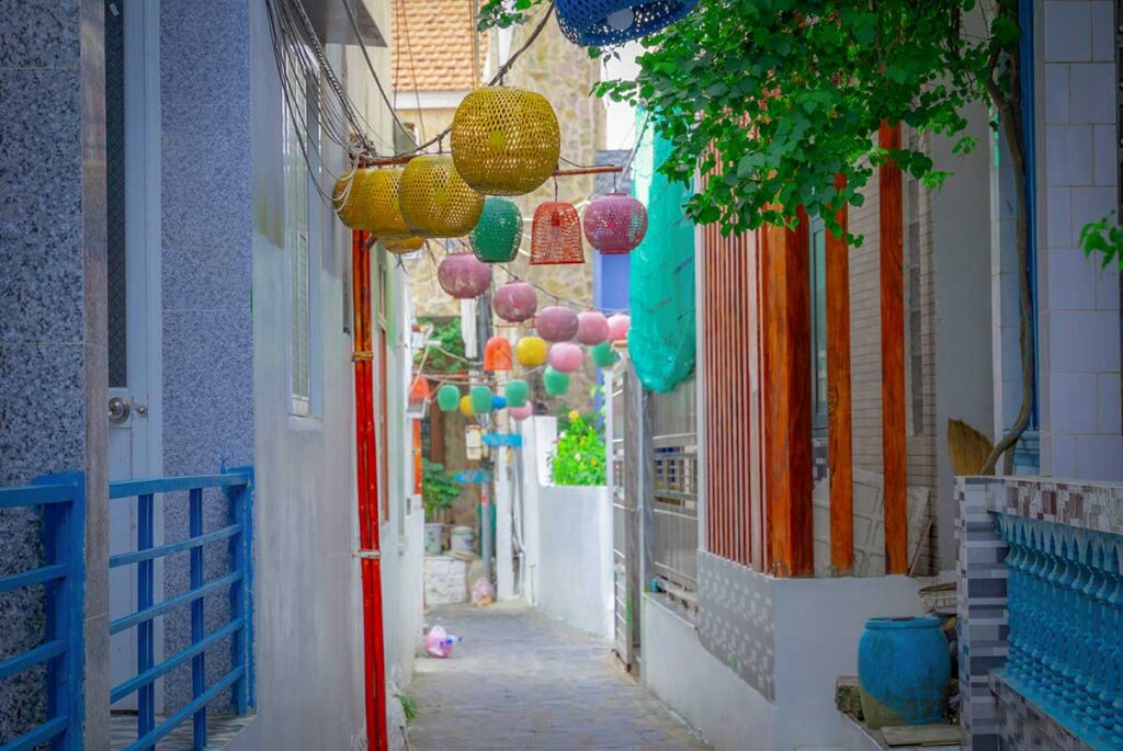 Colorful lanterns hanging in a narrow alley of Nhơn Lý fishing village, Quy Nhon