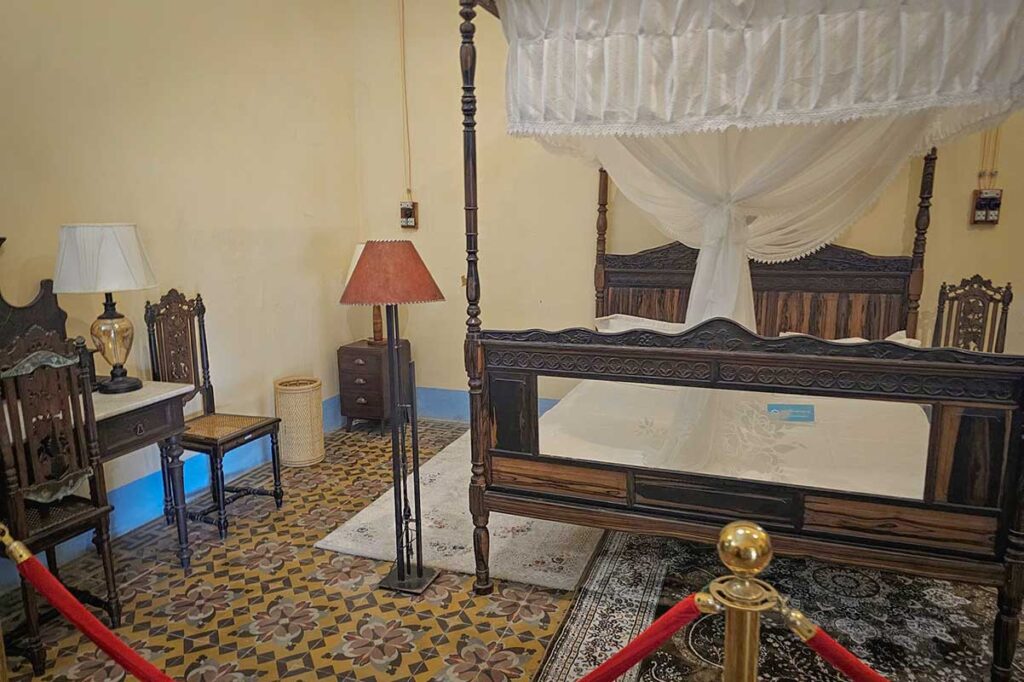 Bedroom inside the Palace of the Island Governor on Con Dao, featuring colonial furniture and a large wooden bed that contrasts with the harsh conditions of the prison camps.
