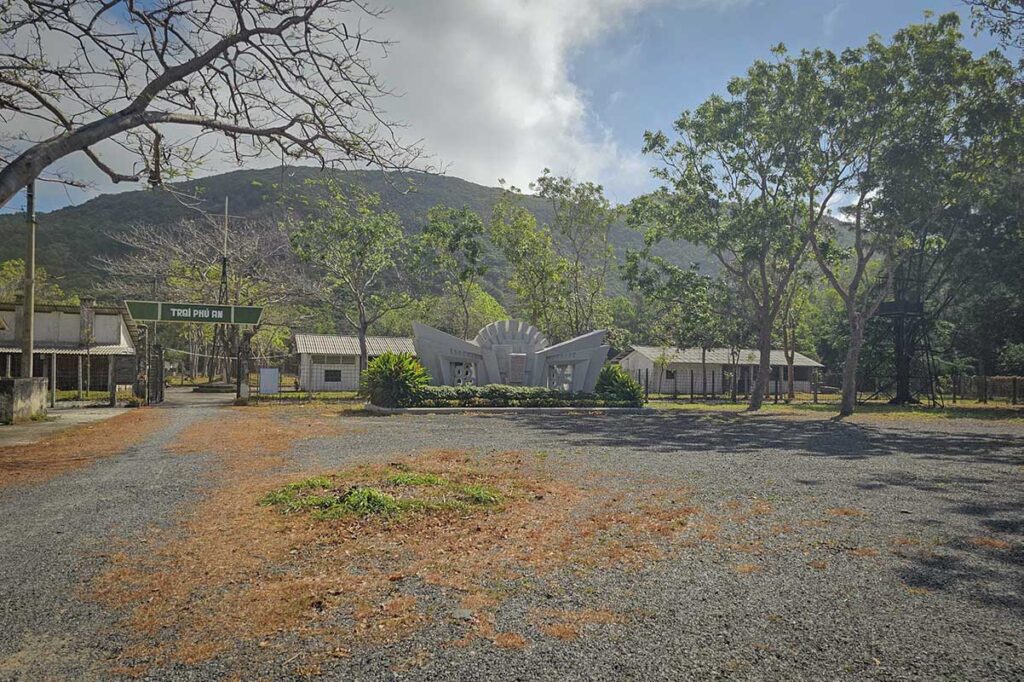 Entrance area of Phu An Prison on Con Dao with memorial structure and surrounding buildings, part of the larger Con Dao prison complex from the Vietnam War period.