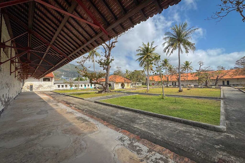 Open courtyard of Phu Son Prison on Con Dao with surrounding buildings and palm trees, showing the spacious layout of one of the oldest parts of the Con Dao prison complex.