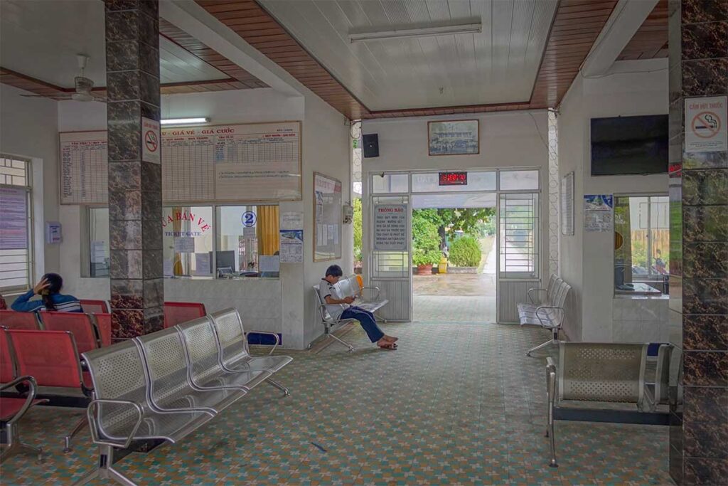 Inside Quy Nhon Railway Station waiting hall with ticket counter, benches, and simple facilities typical of a small provincial station.
