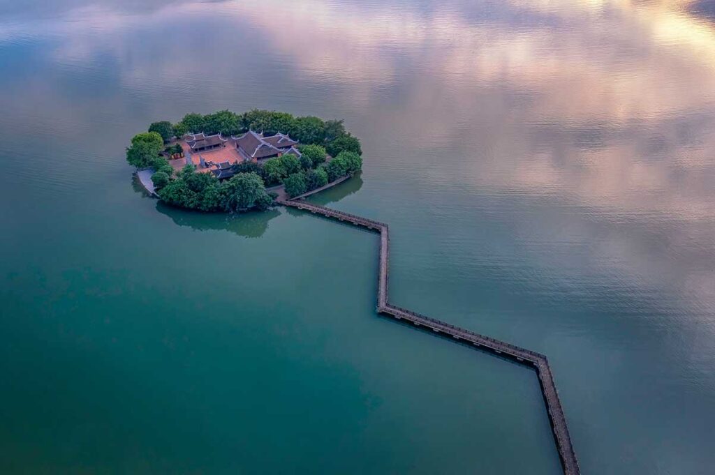 Aerial view of Tam Chuc Communal House on an island and walking path over the water to another island of Tam Chuc Pagoda Complex