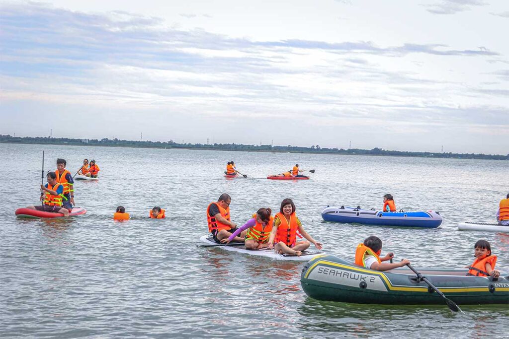 A large group of domestic tourists are playing with sups and inflatable rafts on Tri An Lake