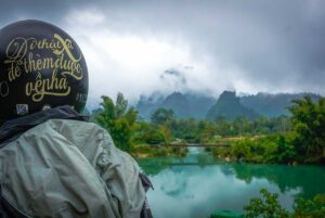 A helmet of a motorbike driver with on the background a stream with mountains along the Cao Bang Loop