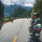 Ha Giang Loop motorbike tour with traveler on the back of an Easy Rider riding along a scenic mountain road