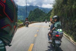 Ha Giang Loop motorbike tour with traveler on the back of an Easy Rider riding along a scenic mountain road