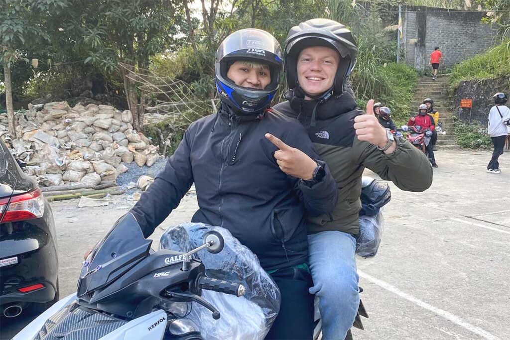 Tourist giving thumbs up while riding with Easy Rider on Ha Giang Loop motorbike tour