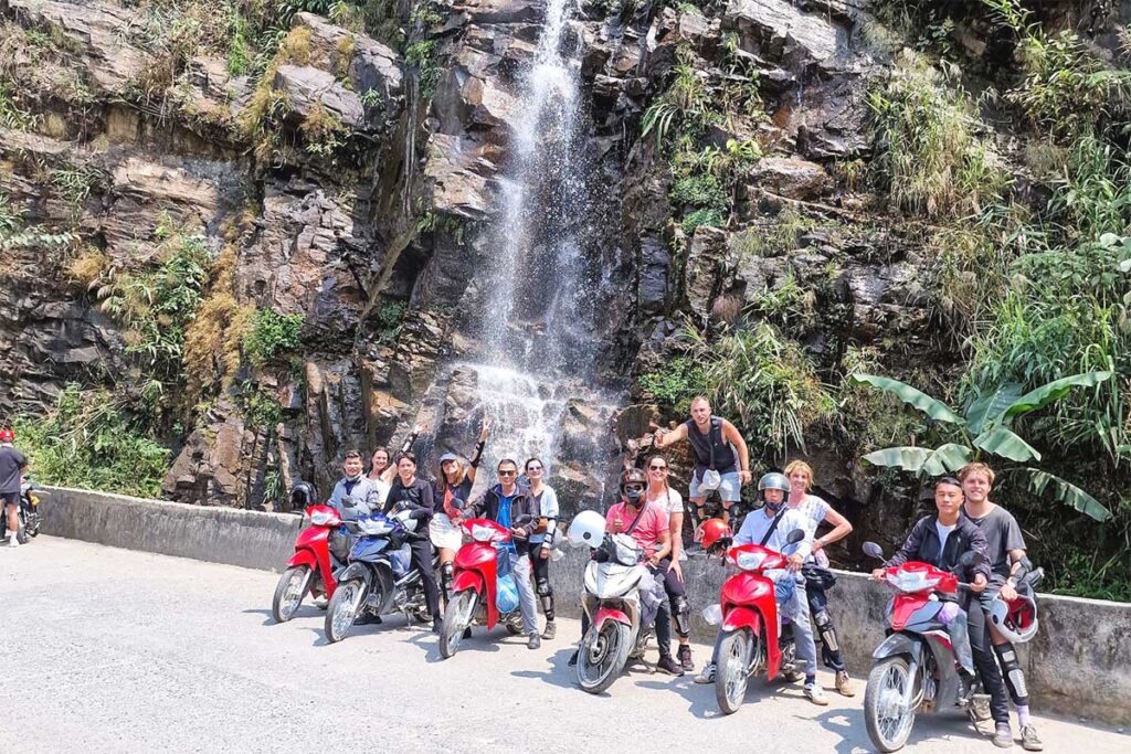 Group photo at a waterfall stop along the Ha Giang Loop motorbike tour with Easy Riders