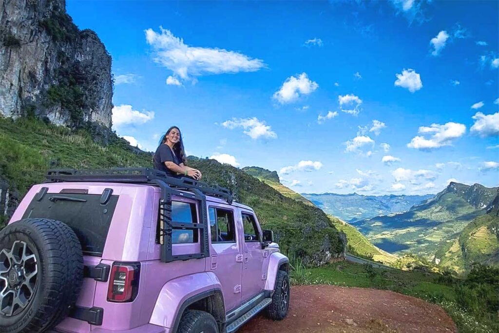 Girl sitting on top of a jeep with panoramic views of Ha Giang mountains