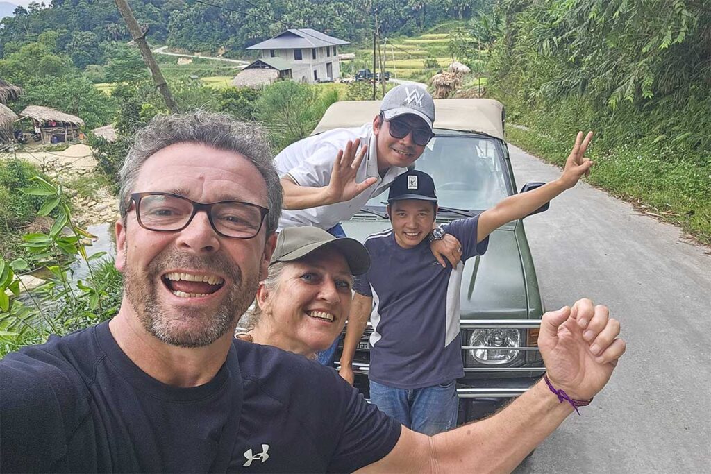 Tourists and local guides posing in front of a military jeep during Ha Giang Loop tour