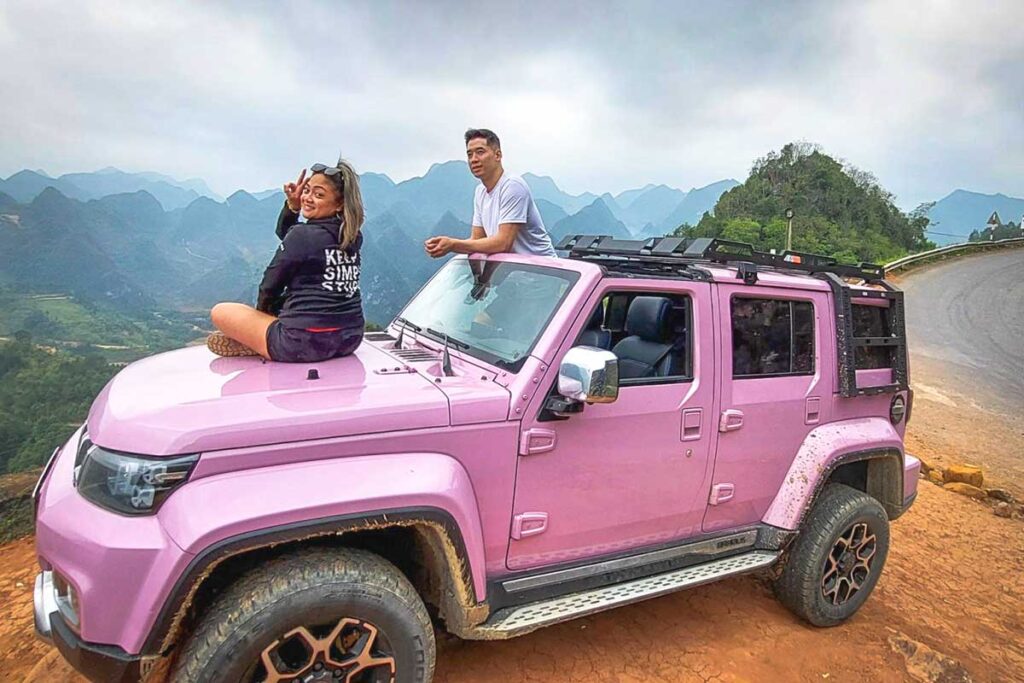 Tourist couple enjoying Ha Giang mountain views from modern jeep with open roof