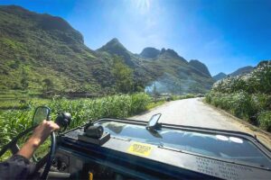 View from inside a military jeep driving along a scenic mountain road in Ha Giang