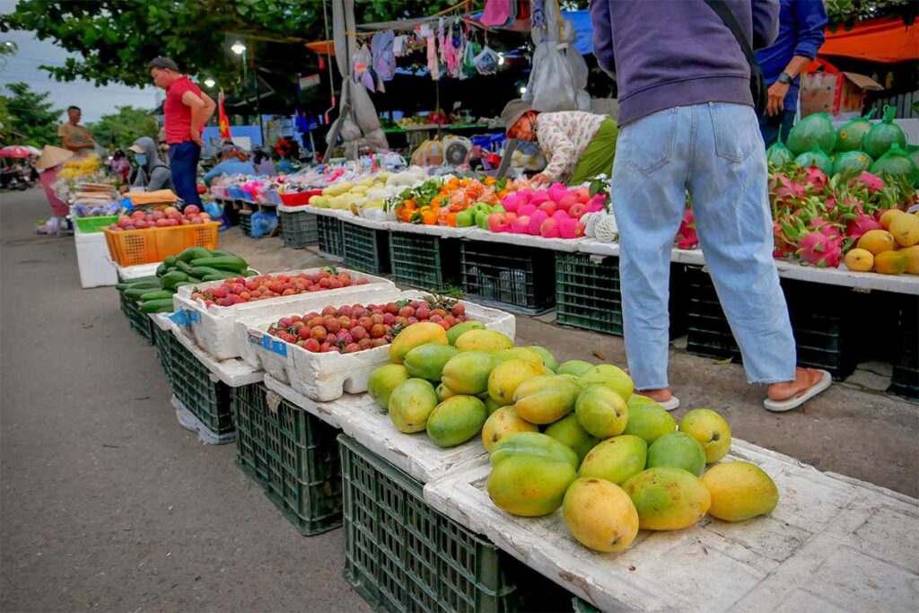Fresh tropical fruits like mango, dragon fruit, and lychee on display at An Bang Market, Hoi An.