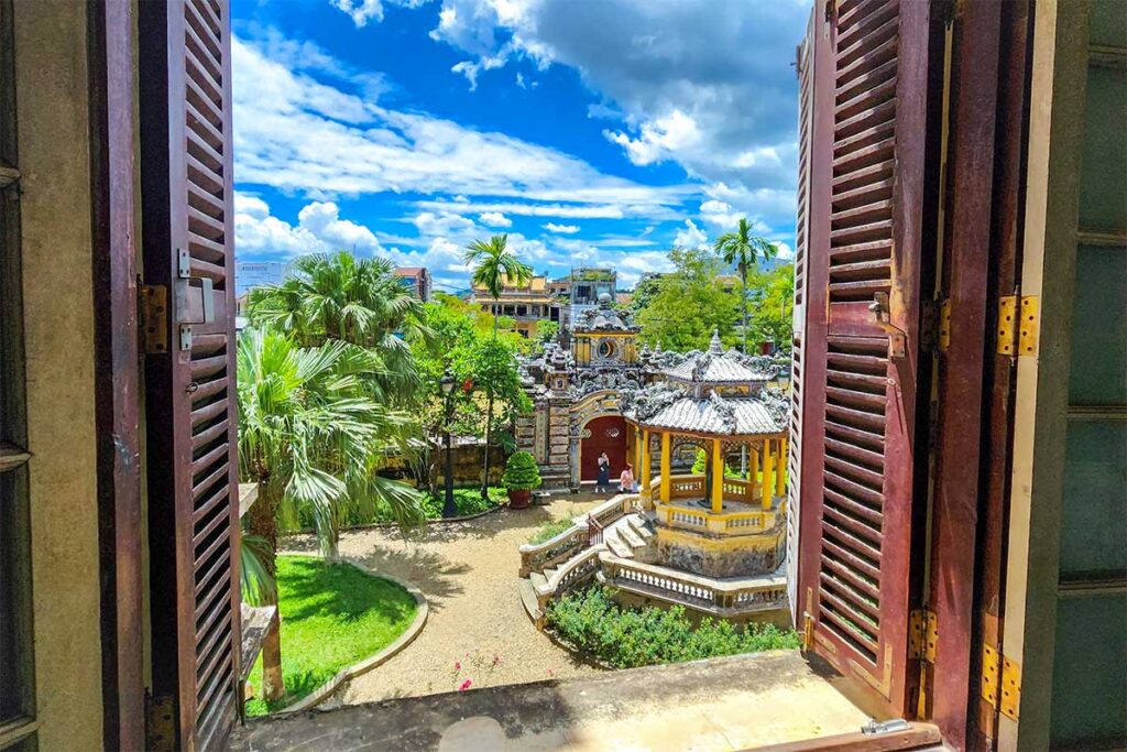 View from inside through the window of An Dinh Palace at the small courtyard and garden of the palace