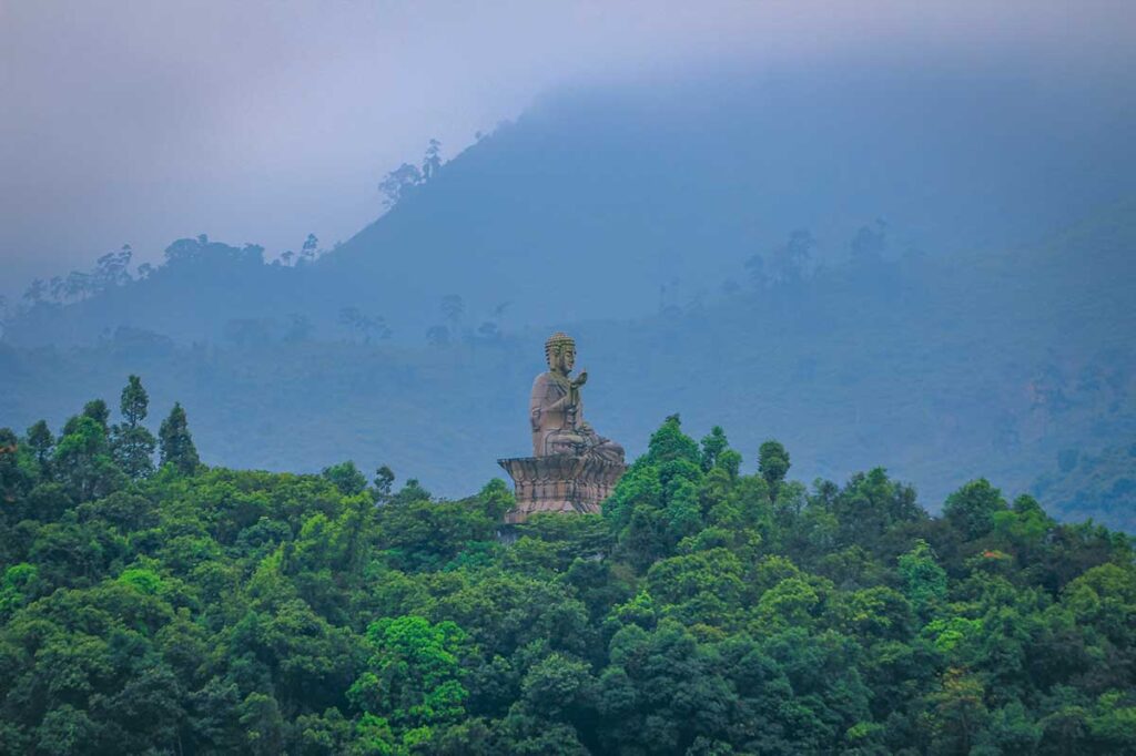 Large stone buddha structure sitting on a hill overlooking the lake - part of Bach Ma Zen Monastery