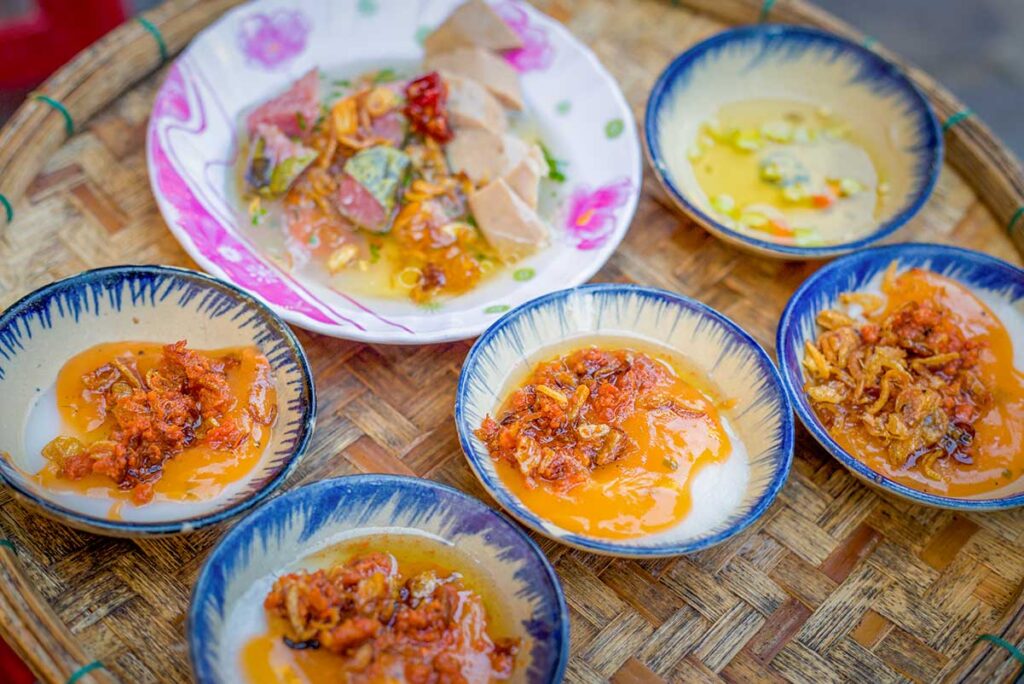 Small bowls of bánh bèo in Hoi An, steamed rice cakes topped with dried shrimp, scallions, and crispy shallots, a popular street food snack