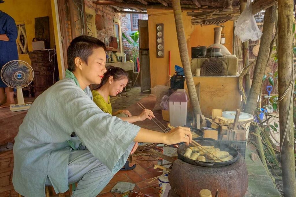 Local women cooking traditional Vietnamese dishes over a wood fire on Cam Kim Island, authentic culinary experience near Hoi An.