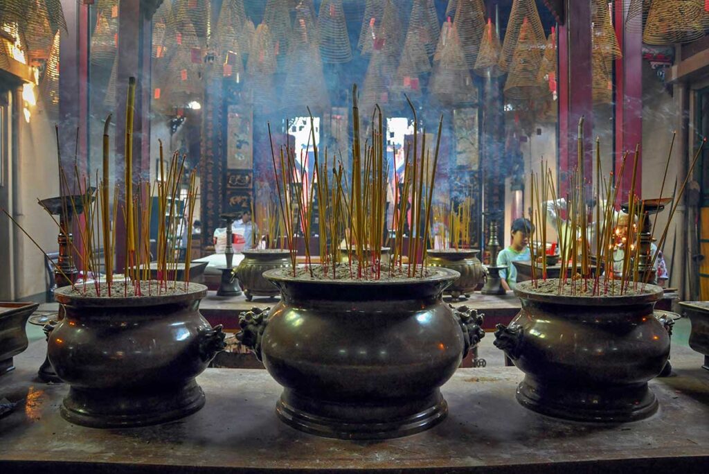 Ornate altar inside Cantonese Assembly Hall Hoi An, decorated with gold lacquer, red pillars, and fresh offerings.