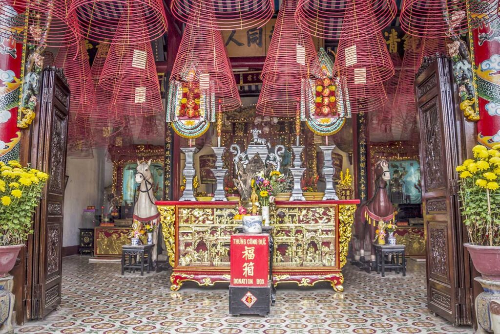 Main hall of the Cantonese Assembly Hall with in incense hanging on the roof, an altar and statues