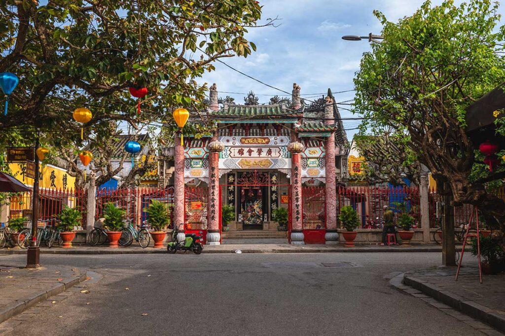 Stone-carved entrance gate of Cantonese Assembly Hall Hoi An with red lanterns and Chinese inscriptions.