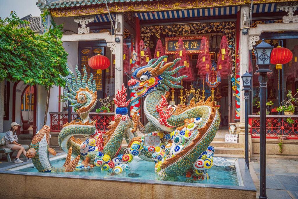 Stone-carved entrance gate of Cantonese Assembly Hall Hoi An with red lanterns and Chinese inscriptions.