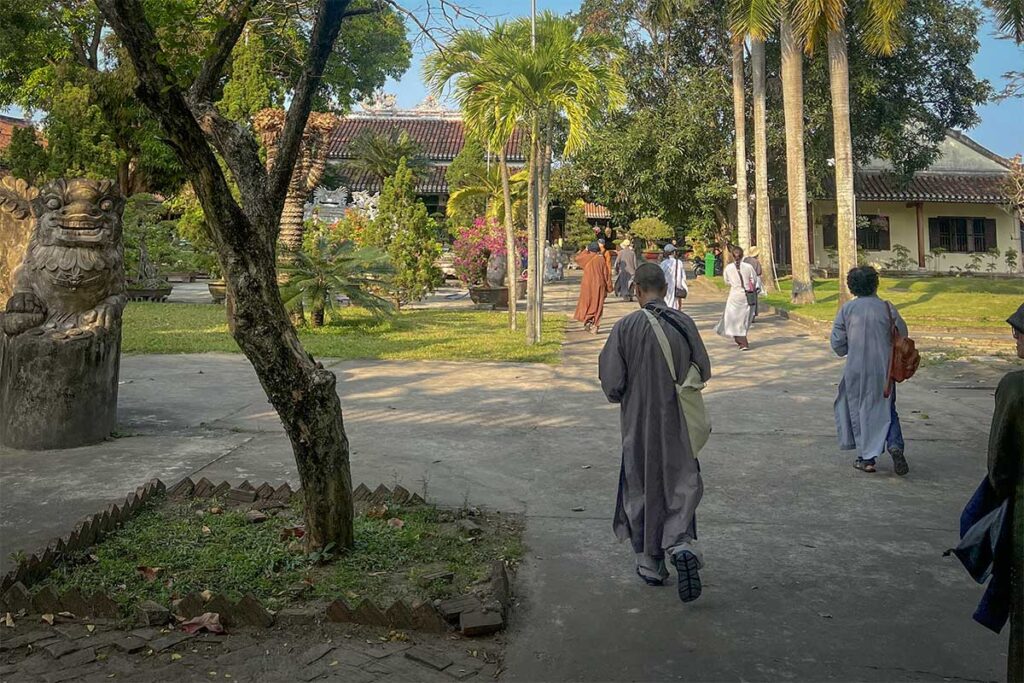 Monks and visitors walking through the peaceful courtyard of Chuc Thanh Pagoda in Hoi An, Vietnam