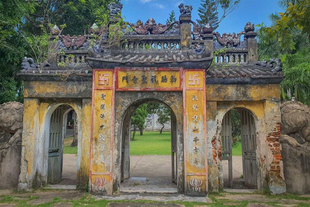 Ancient gate of Chuc Thanh Pagoda in Hoi An with faded yellow walls and carved details – historic Buddhist entrance reflecting centuries of heritage and spiritual charm.