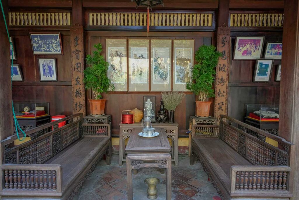 Seating area of Duc An Old House in Hoi An with wooden benches, tea table, and traditional décor creating an authentic atmosphere.