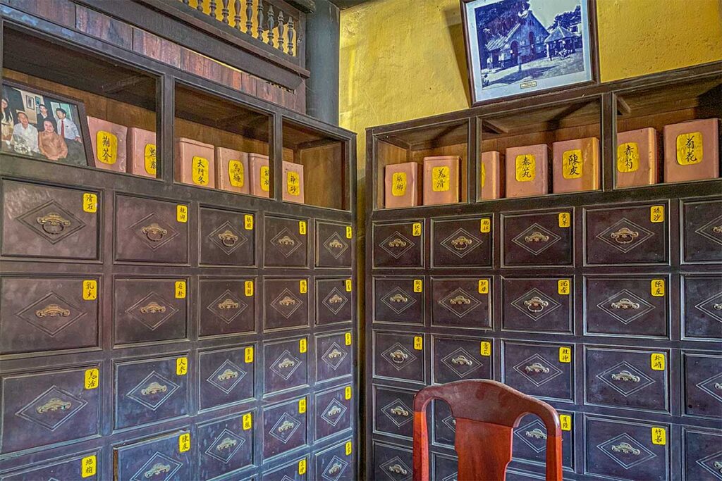 Traditional apothecary cabinet inside Duc An Old House in Hoi An, with rows of labeled drawers used for storing herbal medicine.