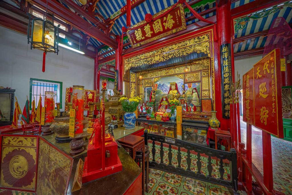 Ornate interior altar of Fujian Assembly Hall in Hoi An with gilded decorations, deity statues, and traditional Chinese lanterns.