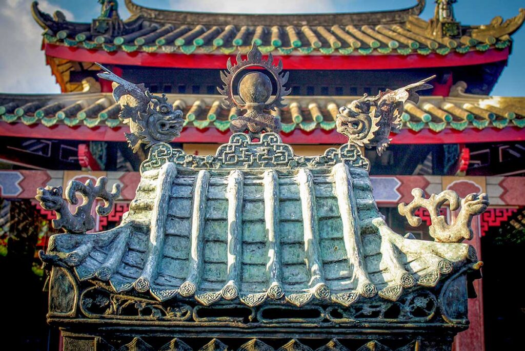 Dragon-carved roof detail of Hai Nam Assembly Hall Hoi An with symbolic ornaments – close-up of intricate craftsmanship blending Taoist and Vietnamese traditions.