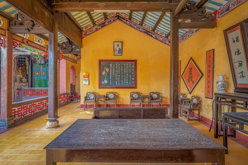 Meeting room at Hai Nam Assembly Hall Hoi An with antique furniture and calligraphy panels – authentic heritage interior showcasing Chinese ancestral traditions.