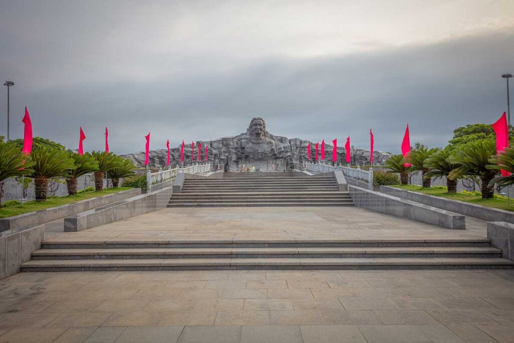 Wide staircase lined with red flags leading to Heroic Mother Thu Monument in Quang Nam.