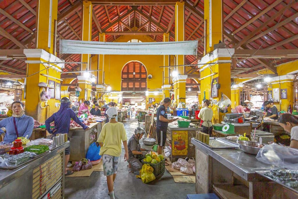 Interior of Hoi An Central Market with food stalls – Fresh produce and meat stalls inside the historic yellow-walled Hoi An Market, bustling with local trade.
