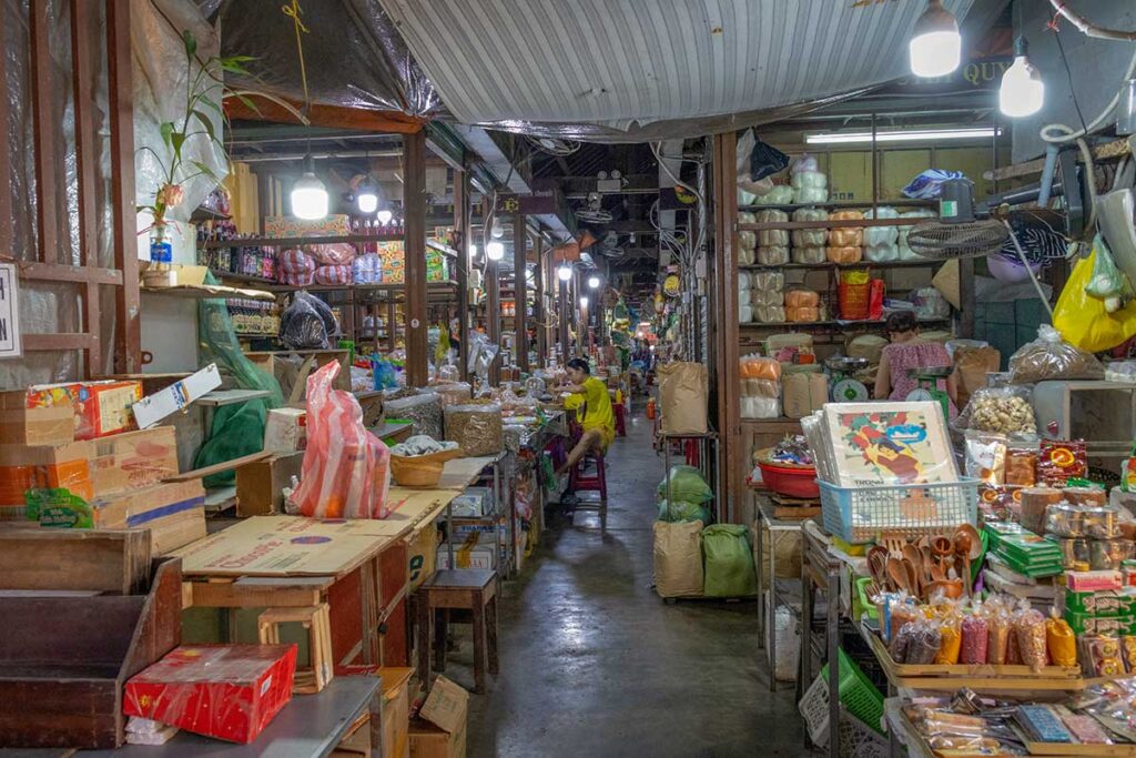 Inside Hoi An Central Market stalls – Narrow passage filled with food stalls, spices, and household goods inside Hoi An Central Market, showcasing its bustling daily trade.