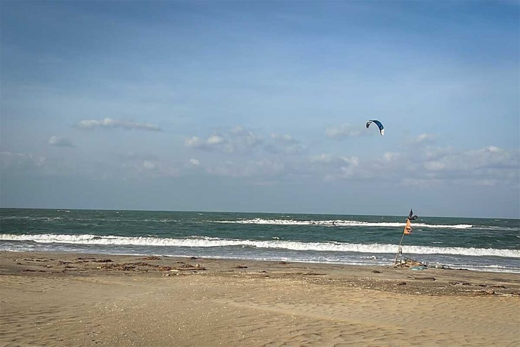 Hoi An Hidden Beach with kitesurfer – A quiet stretch of Hoi An’s Hidden Beach, with waves rolling onto the sand and a colorful kite soaring in the sky, perfect for kiteboarding and relaxation away from the crowds.
