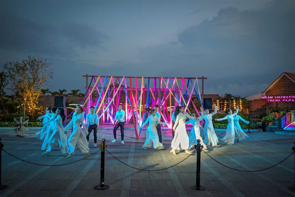 Performers in traditional Vietnamese costumes on an outdoor stage at Hoi An Impression Theme Park.